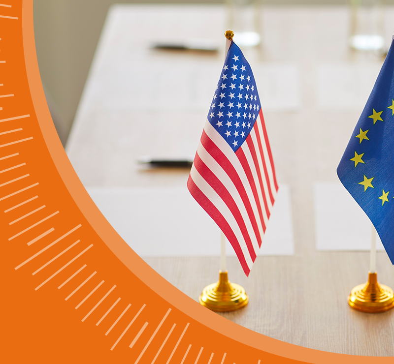 United States and European Union flags standing side by side indoors